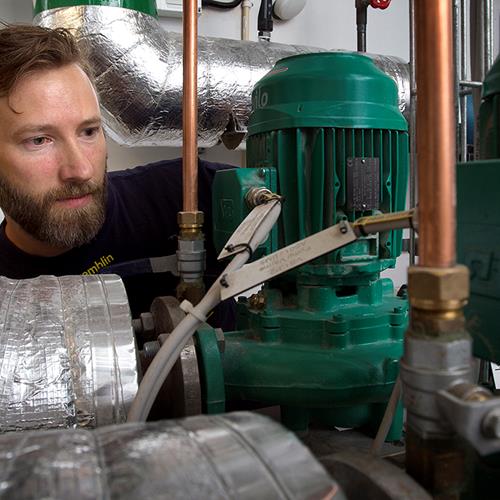 Man i arbetskläder pillar i ett stort silvrigt rör