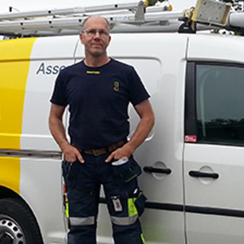 Brandad Assemblin-bil med en man i arbetskläder stående framför